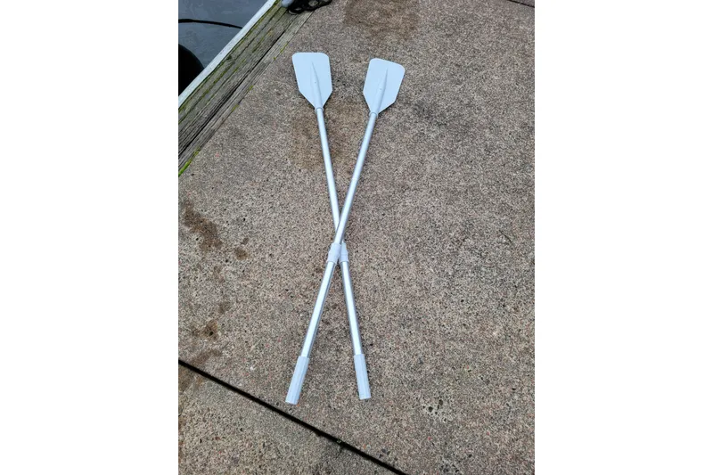 Slide: The Image of Two crossed oars on a concrete surface, near a dock. - 15