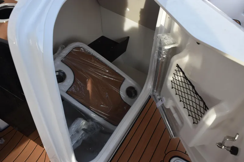 Slide: The Image of 2026 Yamaha Boats 252SD storage compartment with wooden table and netted pocket. - 18