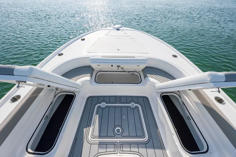 Slide: The Image of 2024 Caymas 26 HB boat deck with open storage compartments on calm water. - 13
