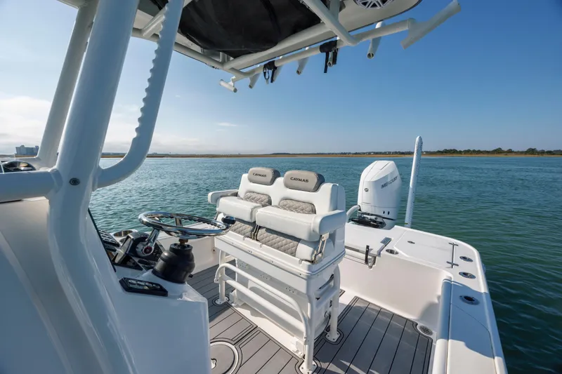 Slide: The Image of 2024 Caymas 26 HB boat interior with helm and seating on calm water. - 17