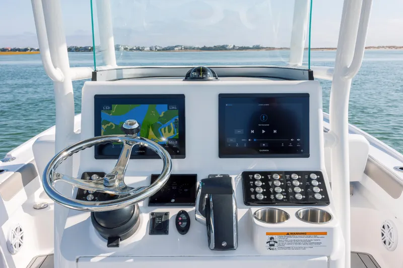 Slide: The Image of 2024 Caymas 26 HB boat dashboard with dual Garmin displays and steering wheel. - 25