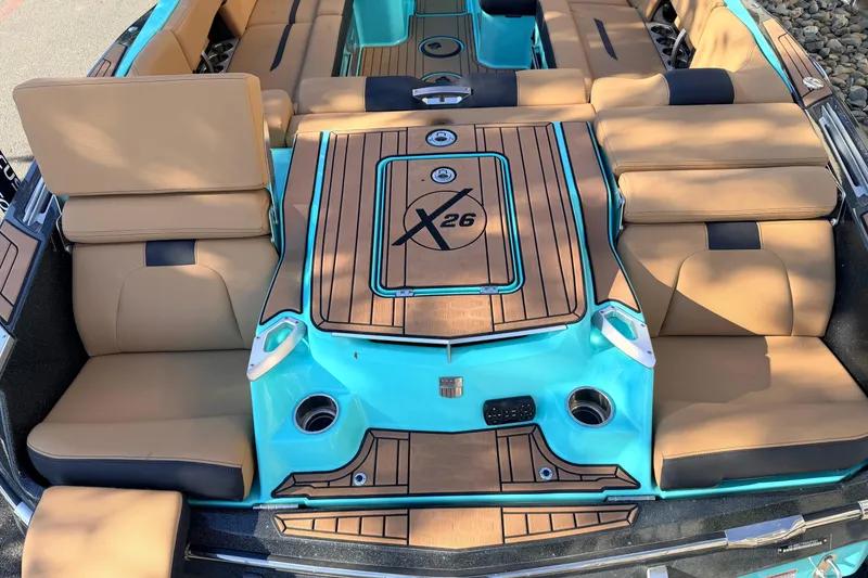 Slide: The Image of 2021 MasterCraft X26 boat interior with tan and turquoise seating, featuring cup holders. - 10