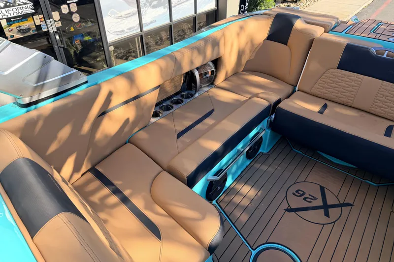 Slide: The Image of 2021 MasterCraft X26 boat interior with tan and black seating, cup holders, and custom flooring. - 15