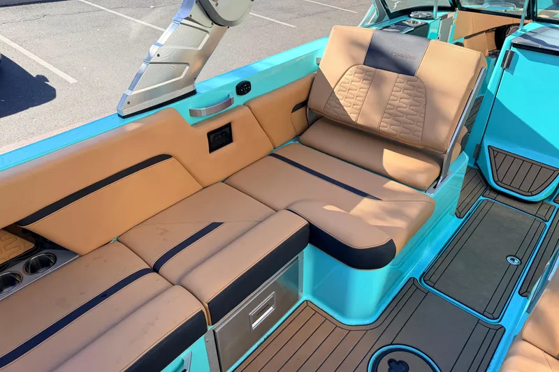Slide: The Image of 2021 MasterCraft X26 boat interior with tan and teal seating, cup holders, and storage. - 18