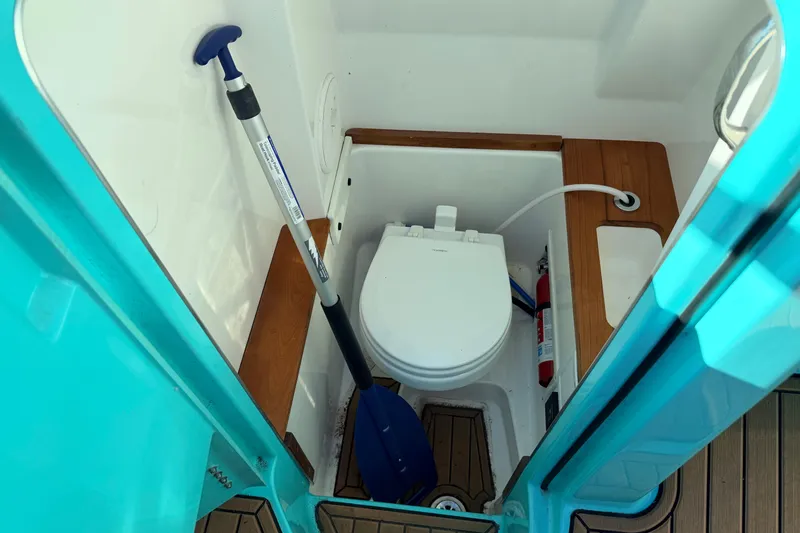 Slide: The Image of 2021 MasterCraft X26 boat bathroom with toilet, paddle, and fire extinguisher. - 20