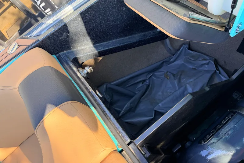 Slide: The Image of 2021 MasterCraft X26 interior storage compartment with tan and black seating. - 27