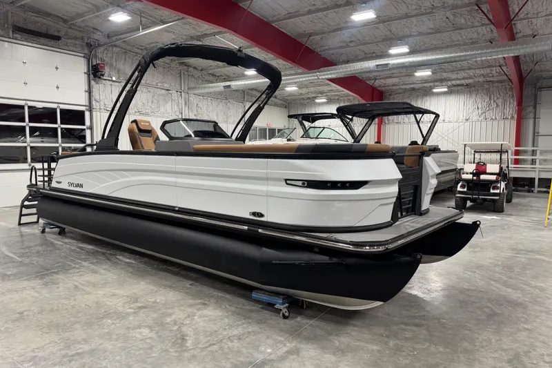 Slide: The Image of 2026 Sylvan L-5 pontoon boat in a spacious indoor showroom. - 2