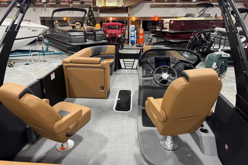 Slide: The Image of 2026 Sylvan L-5 boat interior with tan seats and modern dashboard in showroom. - 7