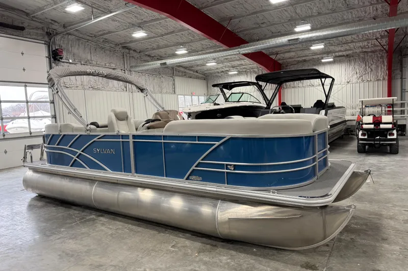 The Image of 2025 Sylvan 8522 Mirage pontoon boat in a showroom, featuring a sleek blue design. - 1
