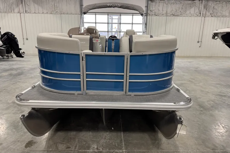 Slide: The Image of 2025 Sylvan 8522 Mirage pontoon boat in a showroom, featuring blue and gray design. - 7