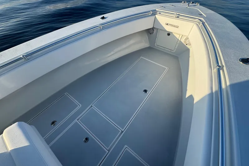 Slide: The Image of 1998 Contender 25 Open boat interior with storage compartments, on calm water. - 16