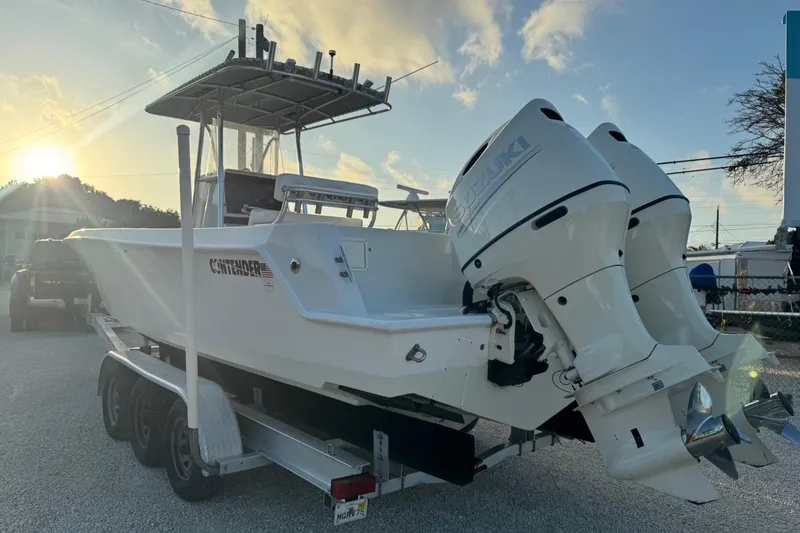 Slide: The Image of 1998 Contender 25 Open boat with dual Suzuki engines on a trailer at sunset. - 20