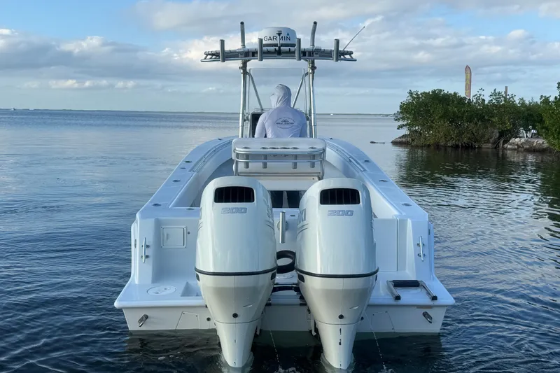 Slide: The Image of 1998 Contender 25 Open boat with dual outboard engines on calm water. - 6