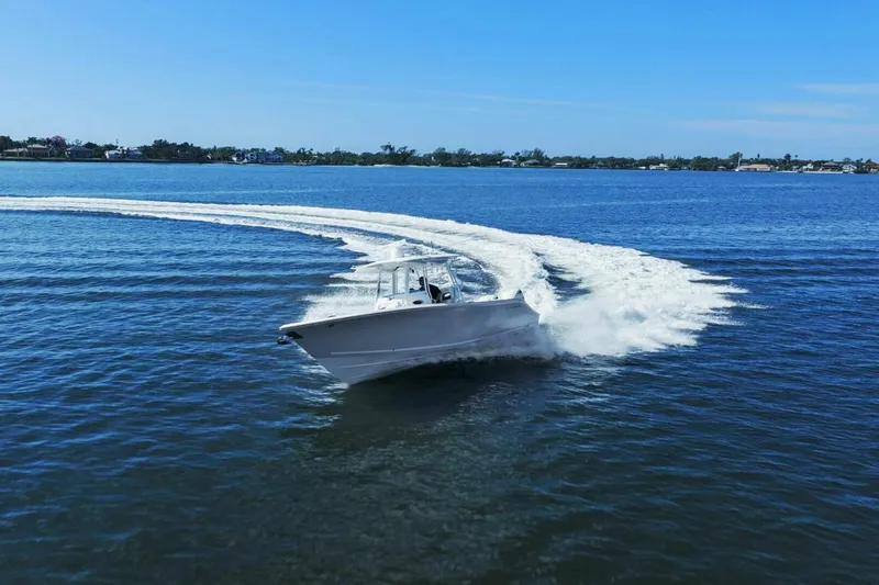 Slide: The Image of 2023 Cobia 301 Center Console boat making a sharp turn on open water. - 31