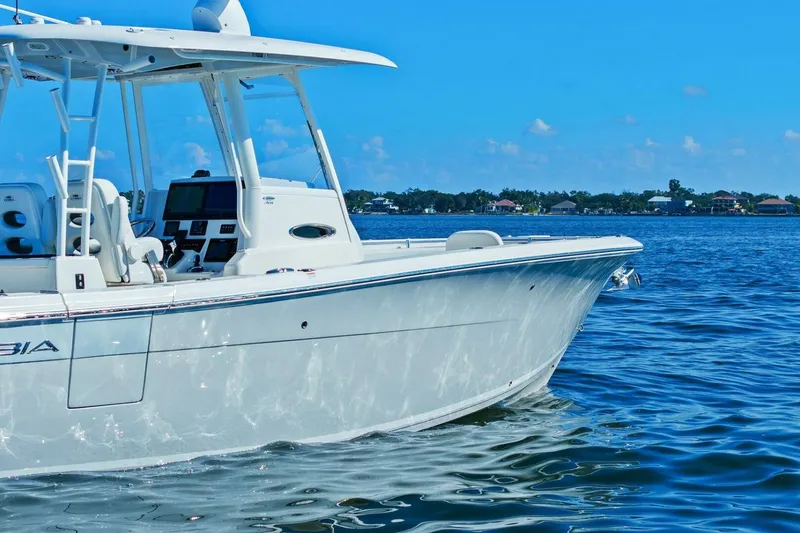 Slide: The Image of 2023 Cobia 301 Center Console boat on calm blue water under clear sky. - 34