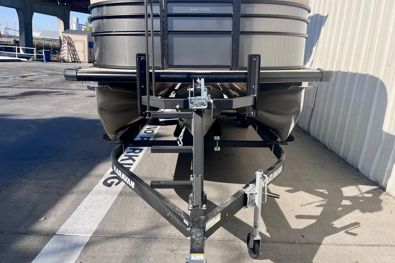 Slide: The Image of 2025 Harris Cruiser 230 boat on a trailer in a parking area. - 3