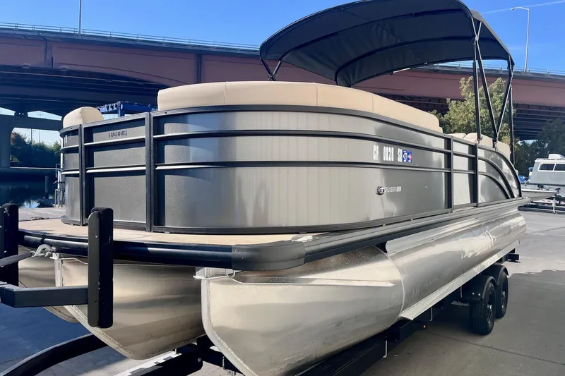 Slide: The Image of 2025 Harris Cruiser 230 pontoon boat on trailer under bridge. - 4