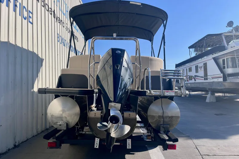 Slide: The Image of 2025 Harris Cruiser 230 pontoon boat, rear view, docked at a marina under clear blue sky. - 6
