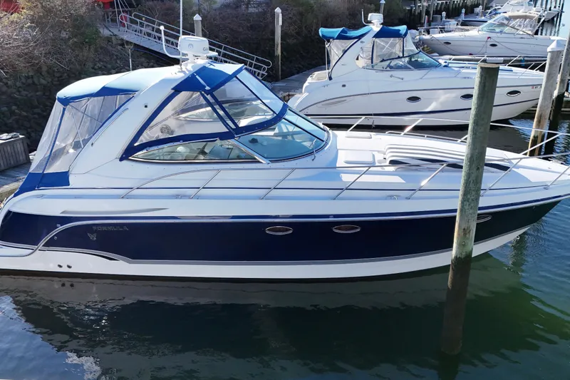 The Image of 2006 Formula 34 Performance Cruiser docked in marina, featuring sleek blue and white design. - 0