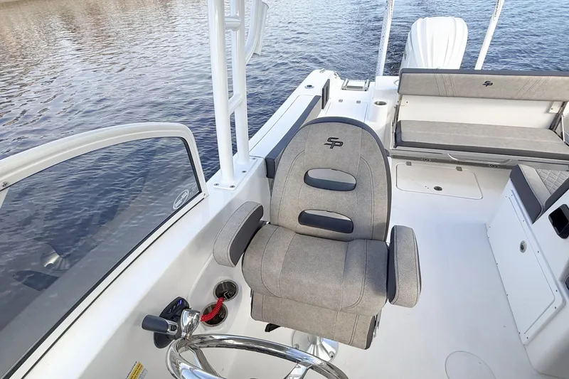 Slide: The Image of 2025 Seapro 240 DLX boat interior with steering wheel and seating, on calm water. - 17