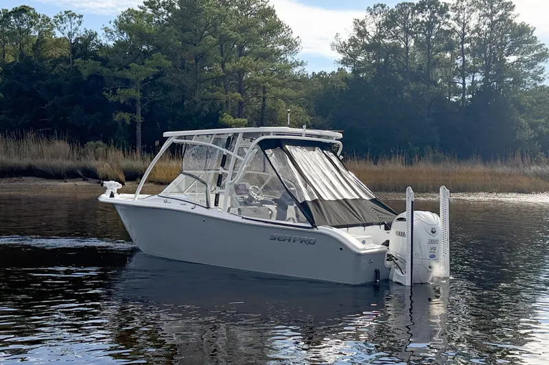 Slide: The Image of 2025 Seapro 240 DLX boat on calm water, surrounded by trees. - 2