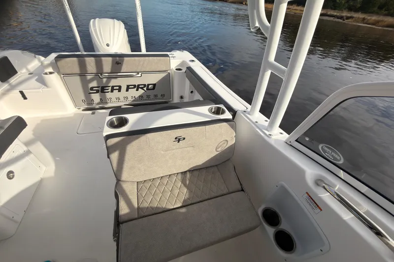 Slide: The Image of 2025 Seapro 240 DLX boat interior with seating and cup holders on a calm water backdrop. - 25