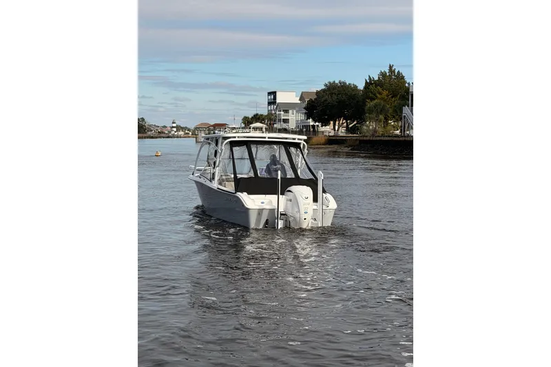 Slide: The Image of 2025 Seapro 240 DLX boat cruising on a calm river near residential area. - 5
