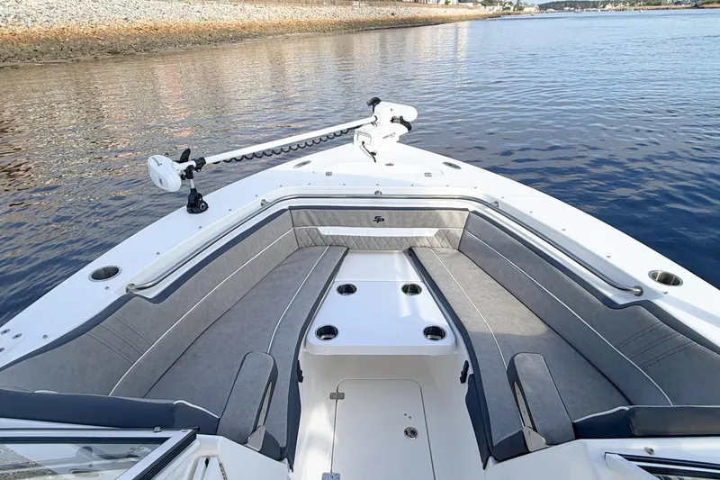 Slide: The Image of 2025 Seapro 240 DLX boat interior with cushioned seating on calm water. - 9