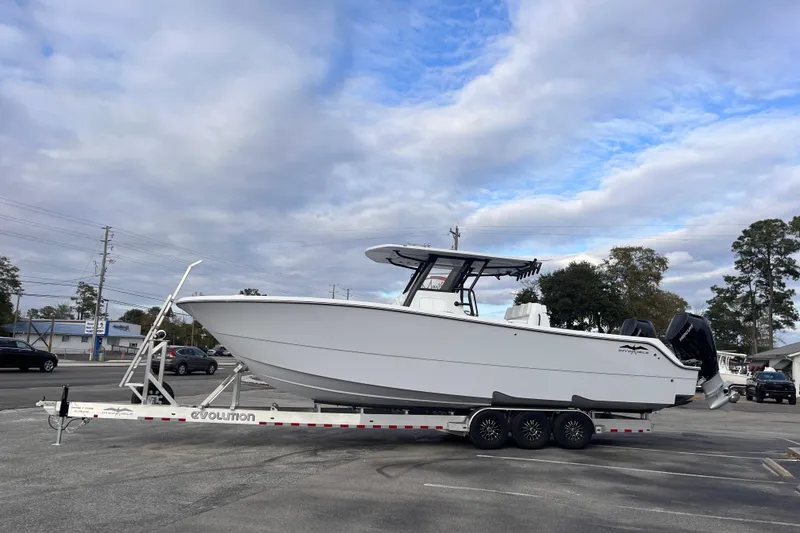 Slide: The Image of 2026 Invincible 33 Catamaran on trailer, parked outdoors under cloudy sky. - 1