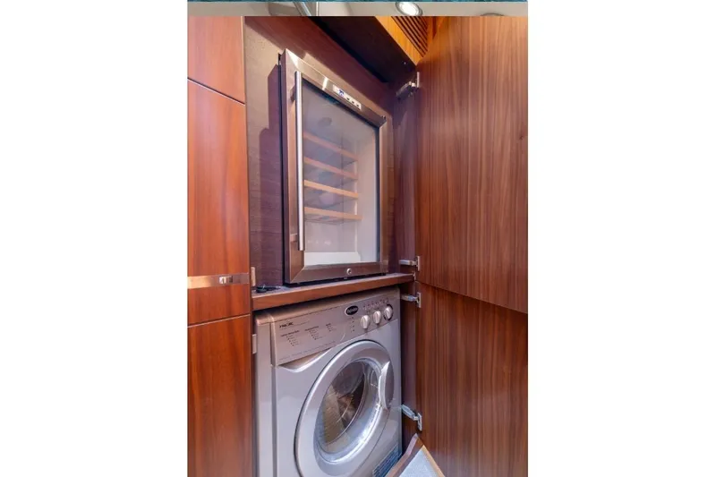 Slide: The Image of Luxury yacht interior with wood paneling, featuring a built-in wine cooler and washing machine. - 18