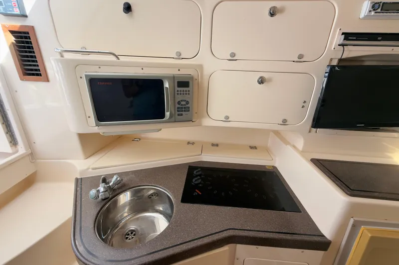 Slide: The Image of 2005 Grady-White Express 330 boat kitchen with sink, microwave, and stove. - 20
