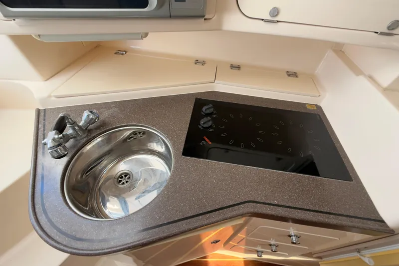 Slide: The Image of 2005 Grady-White Express 330 boat kitchen with sink and stovetop. - 21