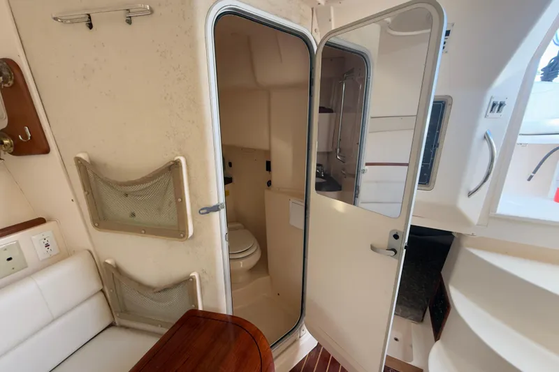 Slide: The Image of 2005 Grady-White Express 330 cabin interior with bathroom and seating area. - 25