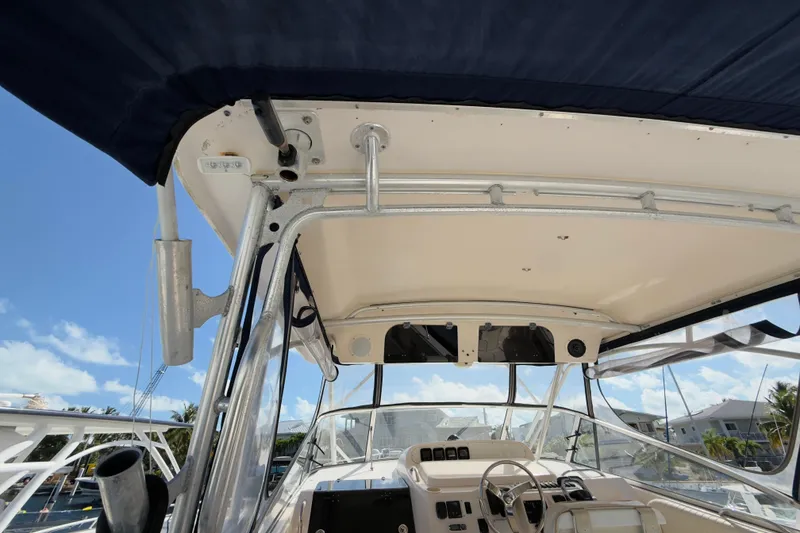 Slide: The Image of 2005 Grady-White Express 330 boat cockpit with canopy, steering wheel, and clear sky background. - 46