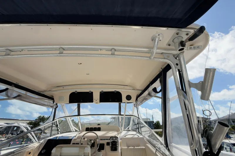 Slide: The Image of 2005 Grady-White Express 330 boat interior with helm and canopy, under clear blue sky. - 47