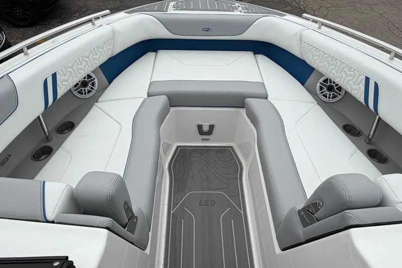 Slide: The Image of 2026 Regal LS9 Surf boat interior with gray and blue seating, cup holders, and speakers. - 10
