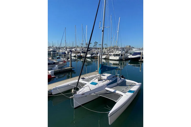 Slide: The Image of 2015 Corsair Dash 750MKII trimaran docked in a marina under clear blue skies. - 2