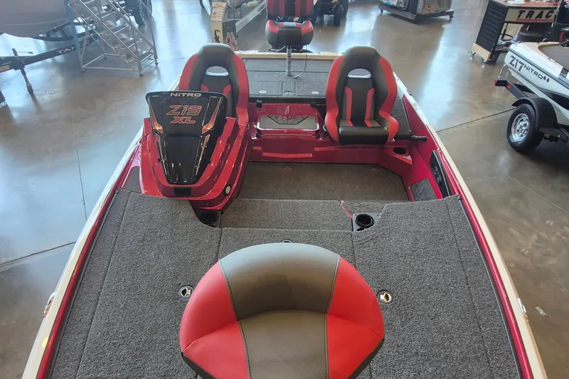 Slide: The Image of 2026 Nitro Z19 XL boat interior with red and gray seating, showcased in a showroom. - 10