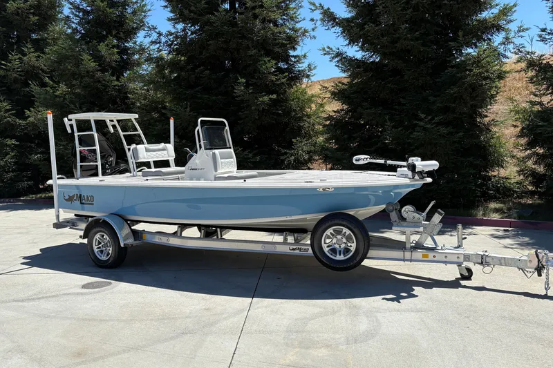 Slide: The Image of 2026 Mako 18 Pro Skiff boat on trailer, parked outdoors, surrounded by trees. - 3