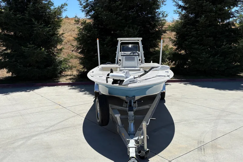 Slide: The Image of 2026 Mako 18 Pro Skiff boat on trailer, parked outdoors near trees. - 6