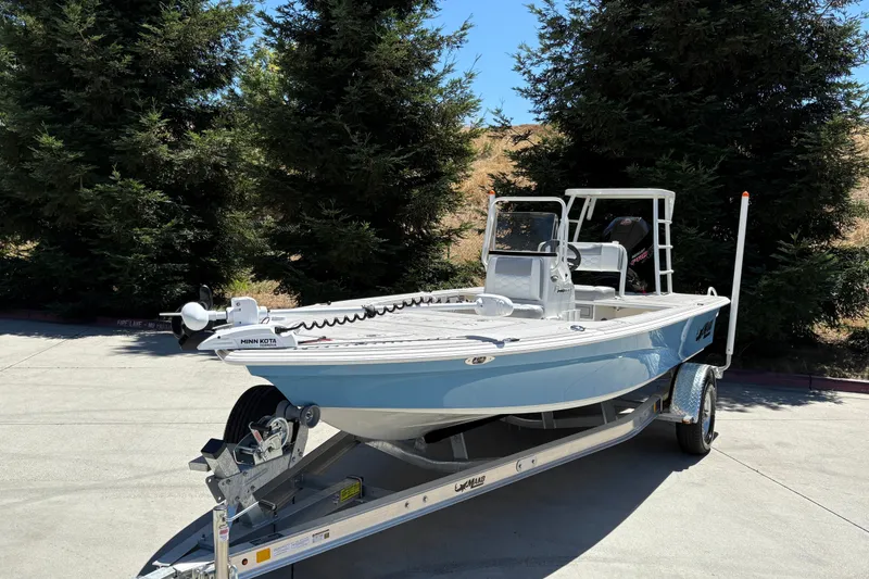 Slide: The Image of 2026 Mako 18 Pro Skiff boat on trailer, parked outdoors near trees. - 8