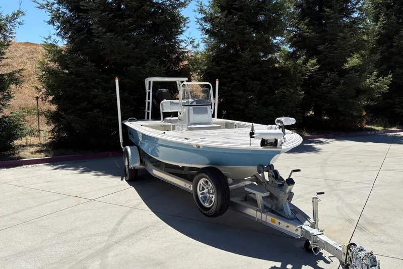 Slide: The Image of 2026 Mako 18 Pro Skiff boat on trailer, parked outdoors near trees. - 7