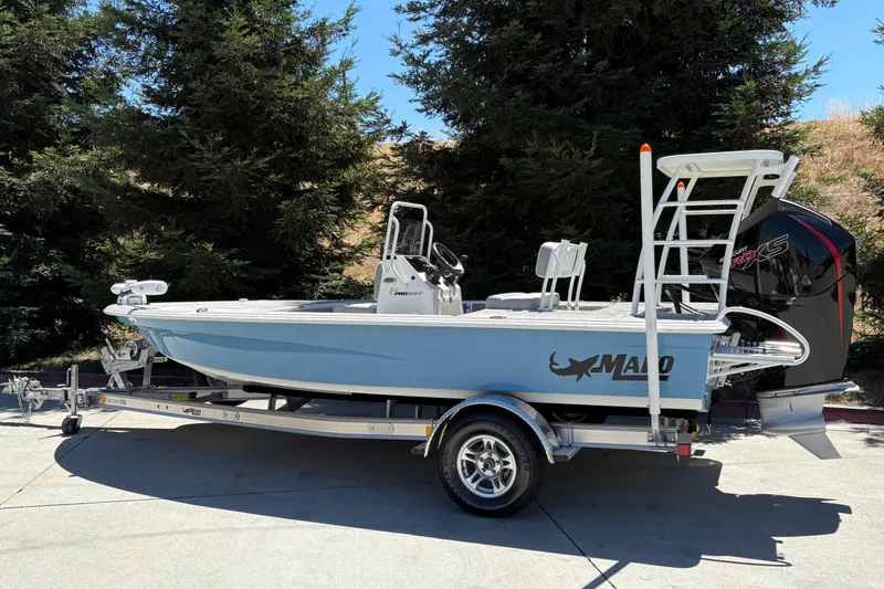 Slide: The Image of 2026 Mako 18 Pro Skiff boat on trailer, parked outdoors with trees in background. - 5