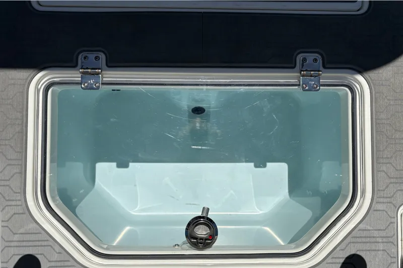 Slide: The Image of Livewell compartment on a 2026 Mako 18 Pro Skiff boat, featuring a clear lid and secure hinges. - 20