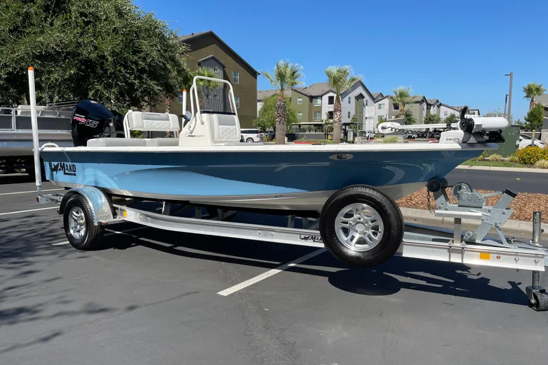 Slide: The Image of 2026 Mako 18 Pro Skiff boat on trailer in parking lot, sunny day. - 2