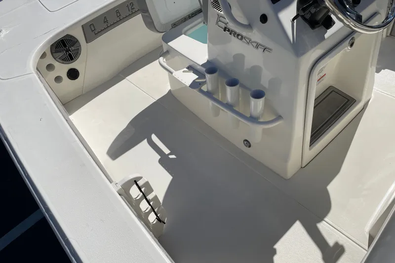 Slide: The Image of Interior view of a 2026 Mako 18 Pro Skiff boat, featuring steering console and rod holders. - 14