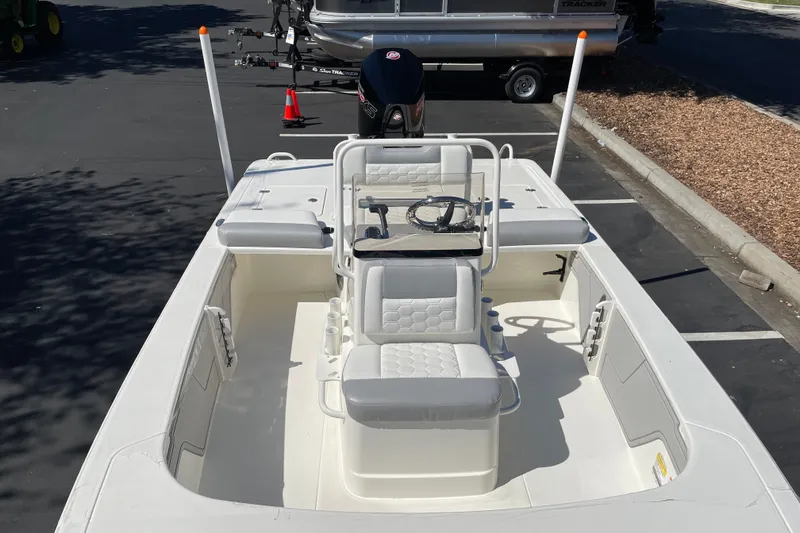 Slide: The Image of 2026 Mako 18 Pro Skiff boat with white seating and steering console in a parking lot. - 7