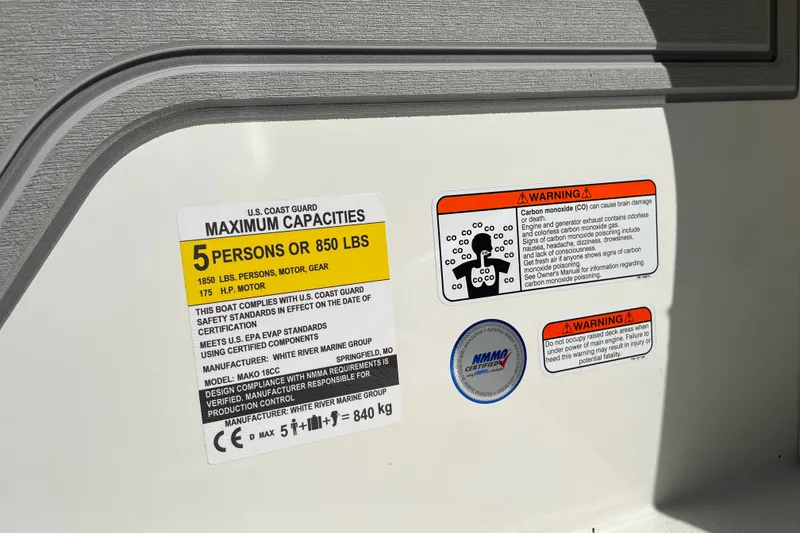 Slide: The Image of 2026 Mako 18 Pro Skiff capacity label, warning signs, and NMMA certification sticker. - 19