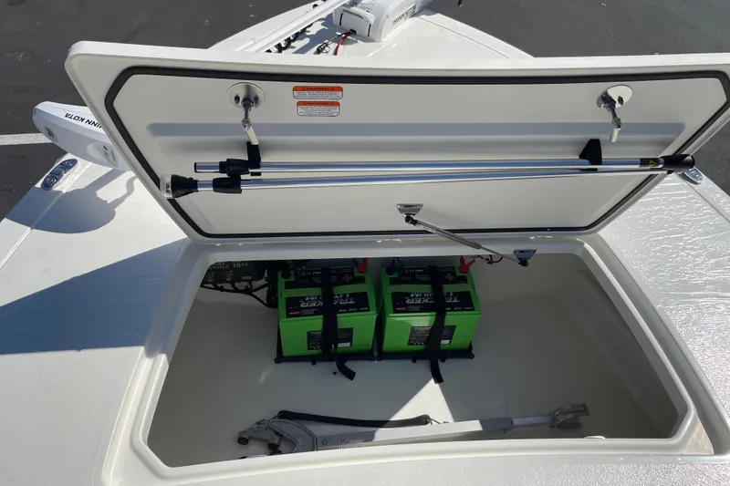 Slide: The Image of Open storage compartment of 2026 Mako 18 Pro Skiff with batteries and tools inside. - 21