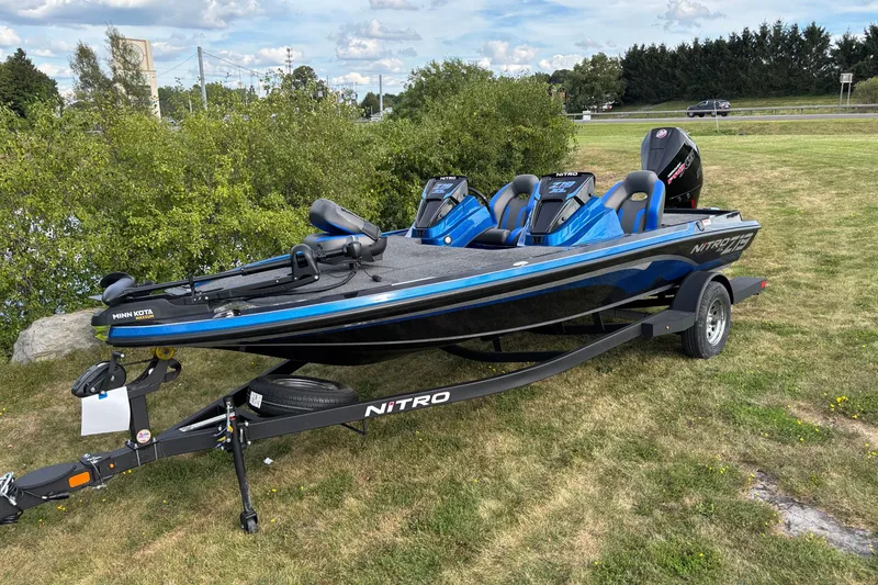 Slide: The Image of 2026 Nitro Z19 XL boat on trailer, blue and black design, parked on grass. - 1